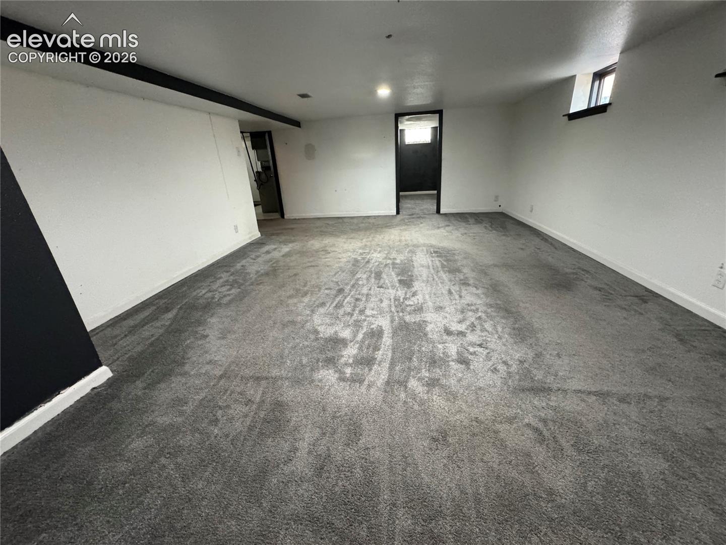 Neutral-toned carpeted interior featuring high-contrast trim, recessed ceiling lighting, and multiple interior doorways