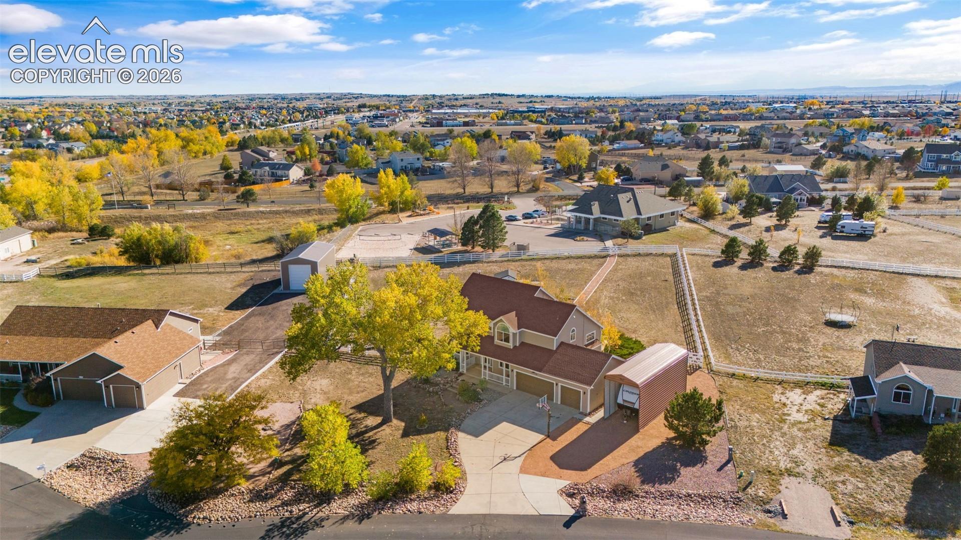 Expansive property featuring a multi-car garage, detached storage structure, covered RV parking, and mature landscaping on a large corner lot