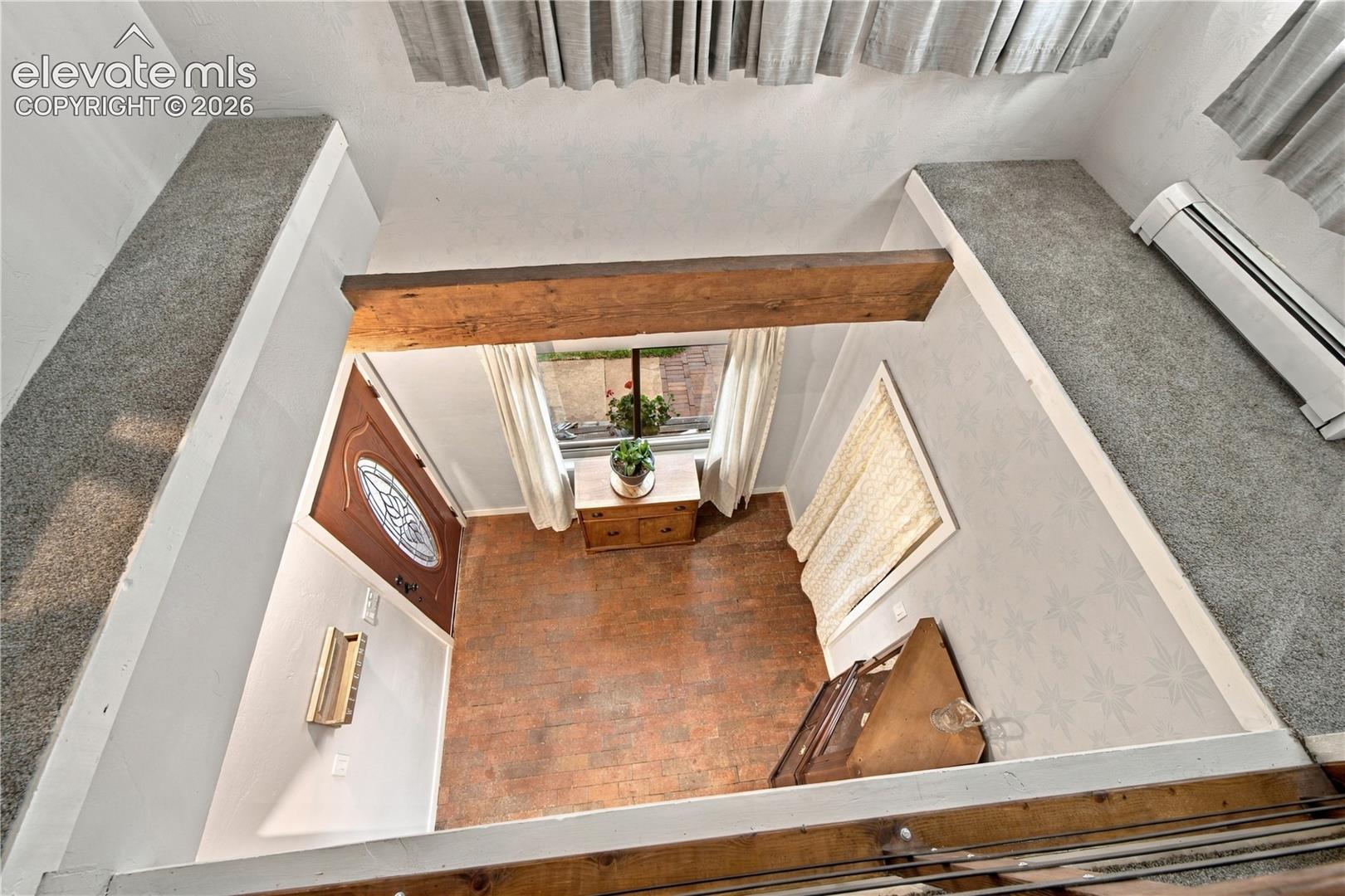 High-ceilinged interior featuring exposed wooden ceiling beams, wood-finish flooring, and carpeted mezzanine ledges