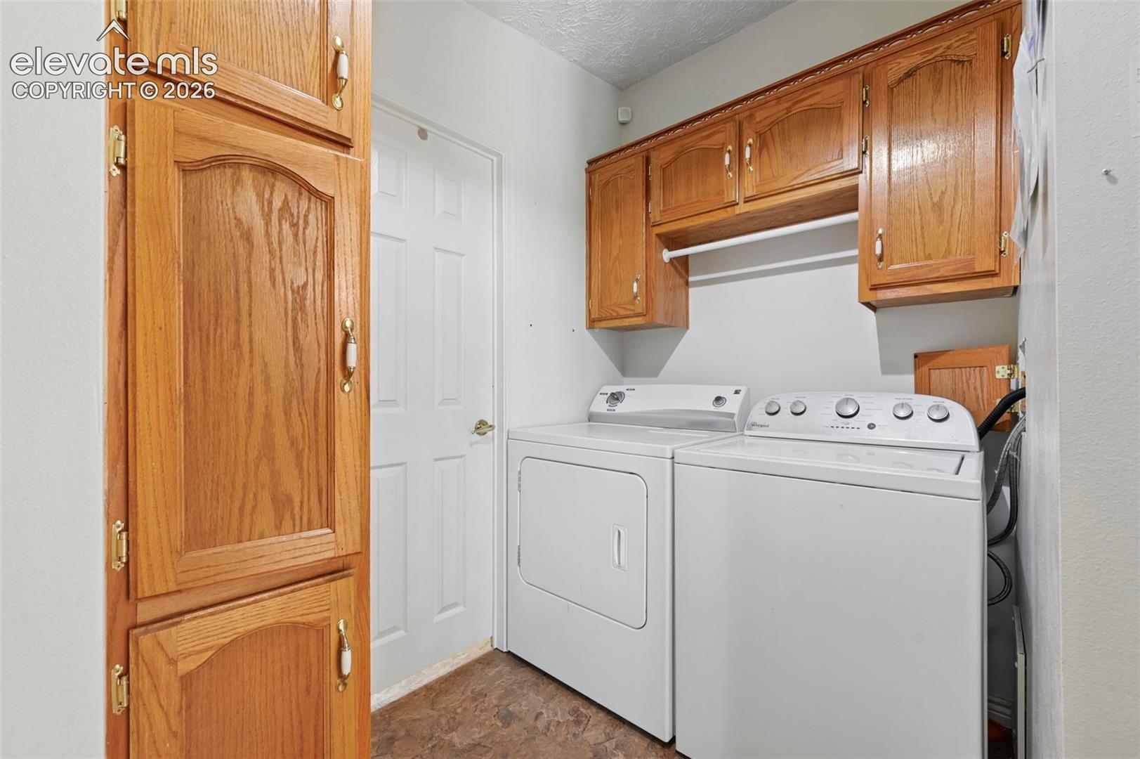 Laundry area with wood-finish cabinetry, white appliances, and a built-in drying rod