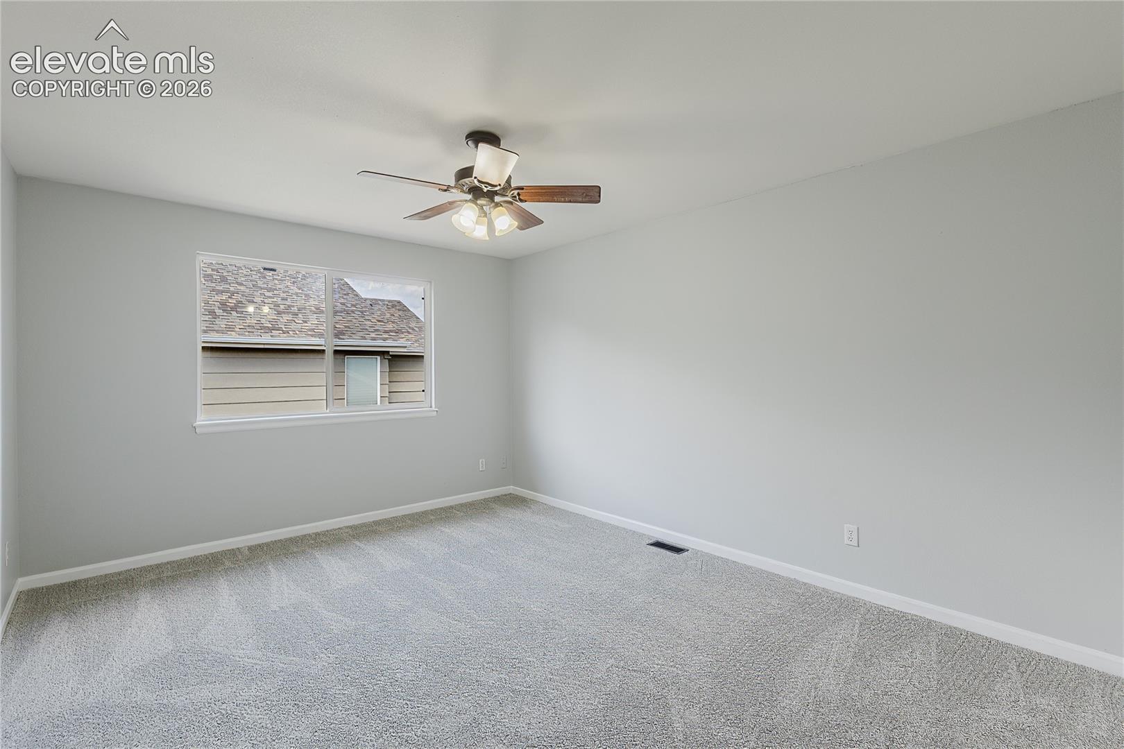 Neutral-toned walls with light grey carpeting, complemented by a ceiling fan with integrated lighting