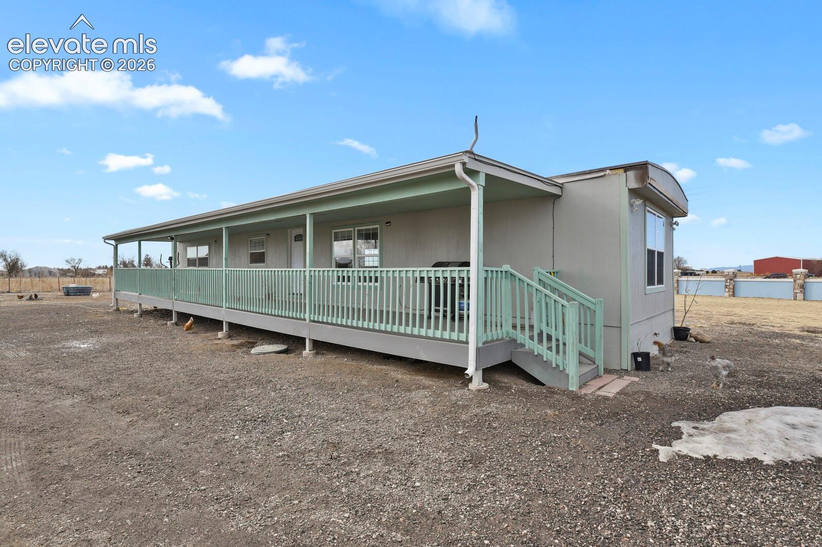 Extended covered deck with wooden railing and integrated staircase, siding exterior, and shingle roofing