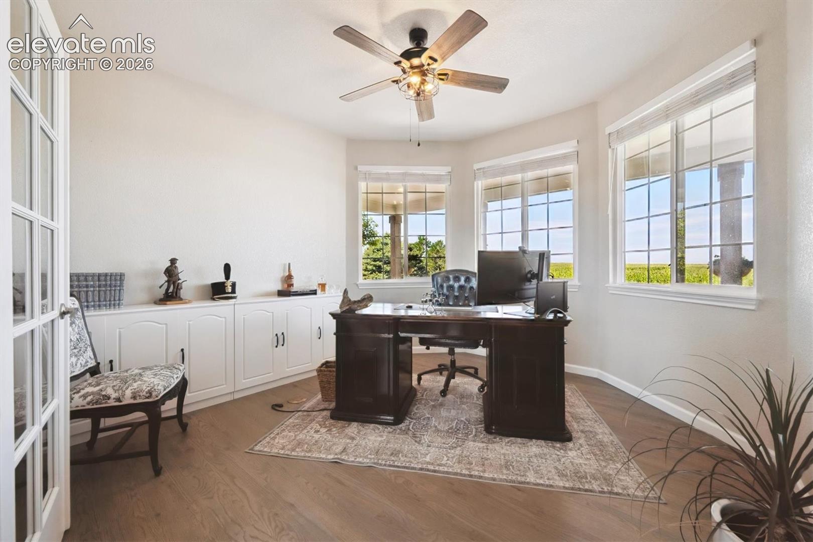 Private room featuring French doors, hardwood flooring, a ceiling fan with integrated lighting, and a built-in cabinetry unit along one wall