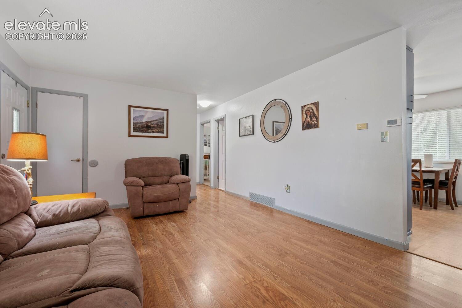 Spacious living area featuring wood-finish flooring, light neutral wall paint, and white trim