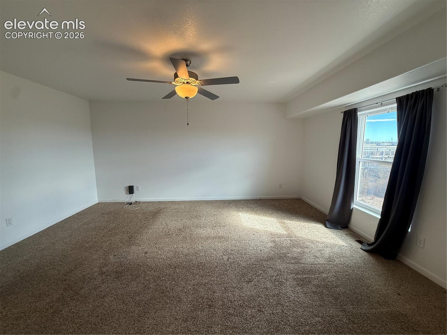 Carpeted interior room featuring a ceiling fan with integrated lighting and a single window