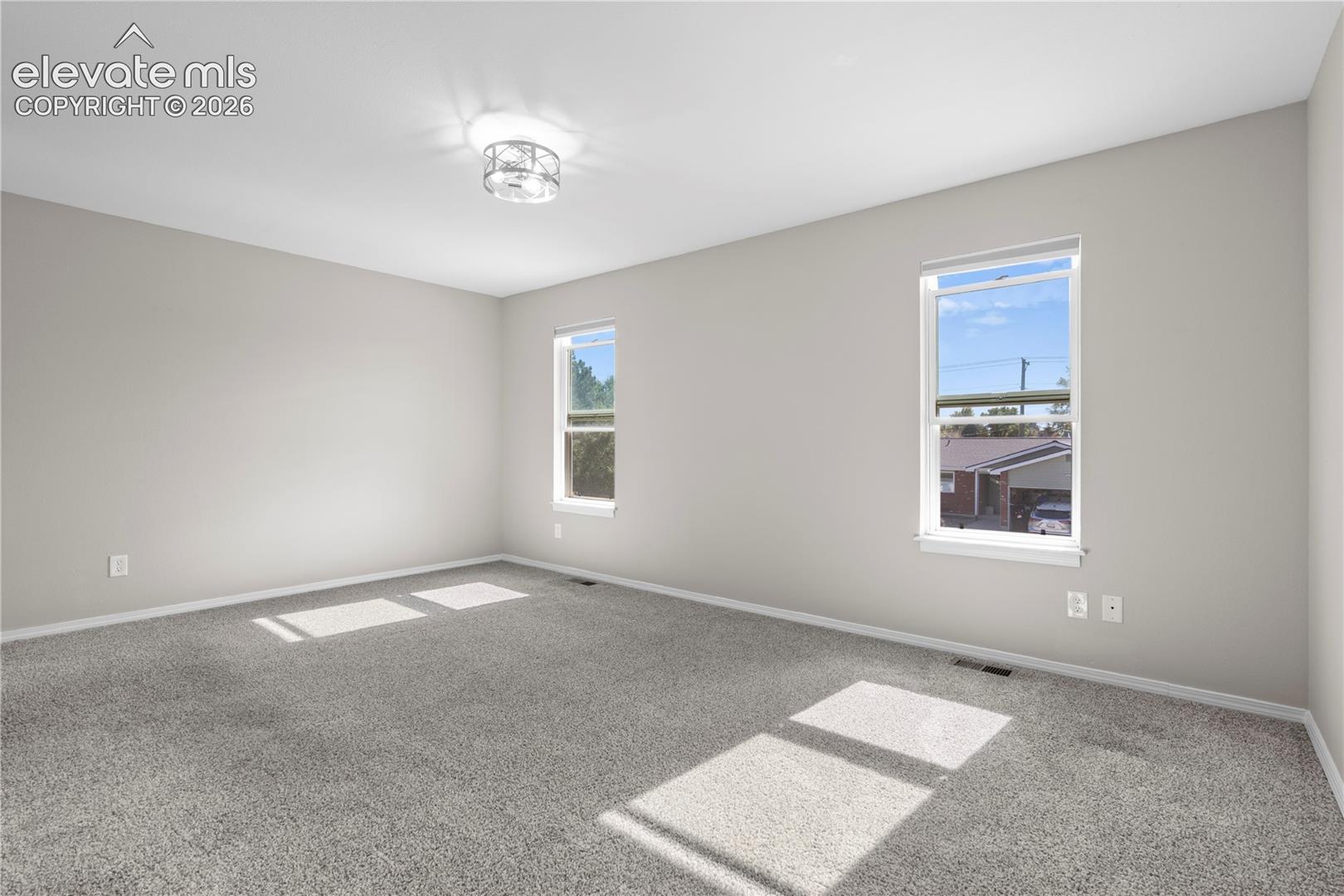 Neutral-toned interior featuring wall-to-wall carpeting, dual-pane windows, and a flush-mount drum ceiling fixture