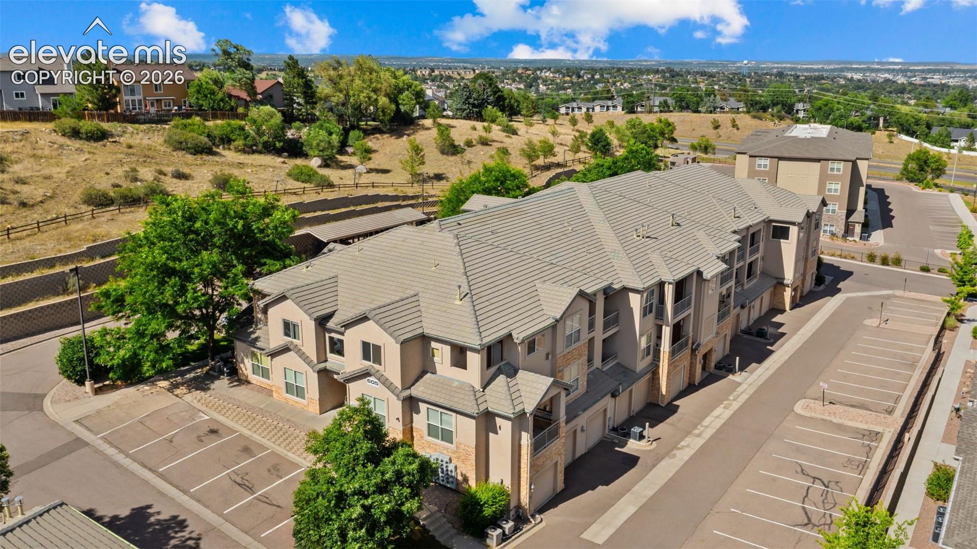 Multi-story residential building featuring a neutral-toned exterior with stone accents and multiple balconies