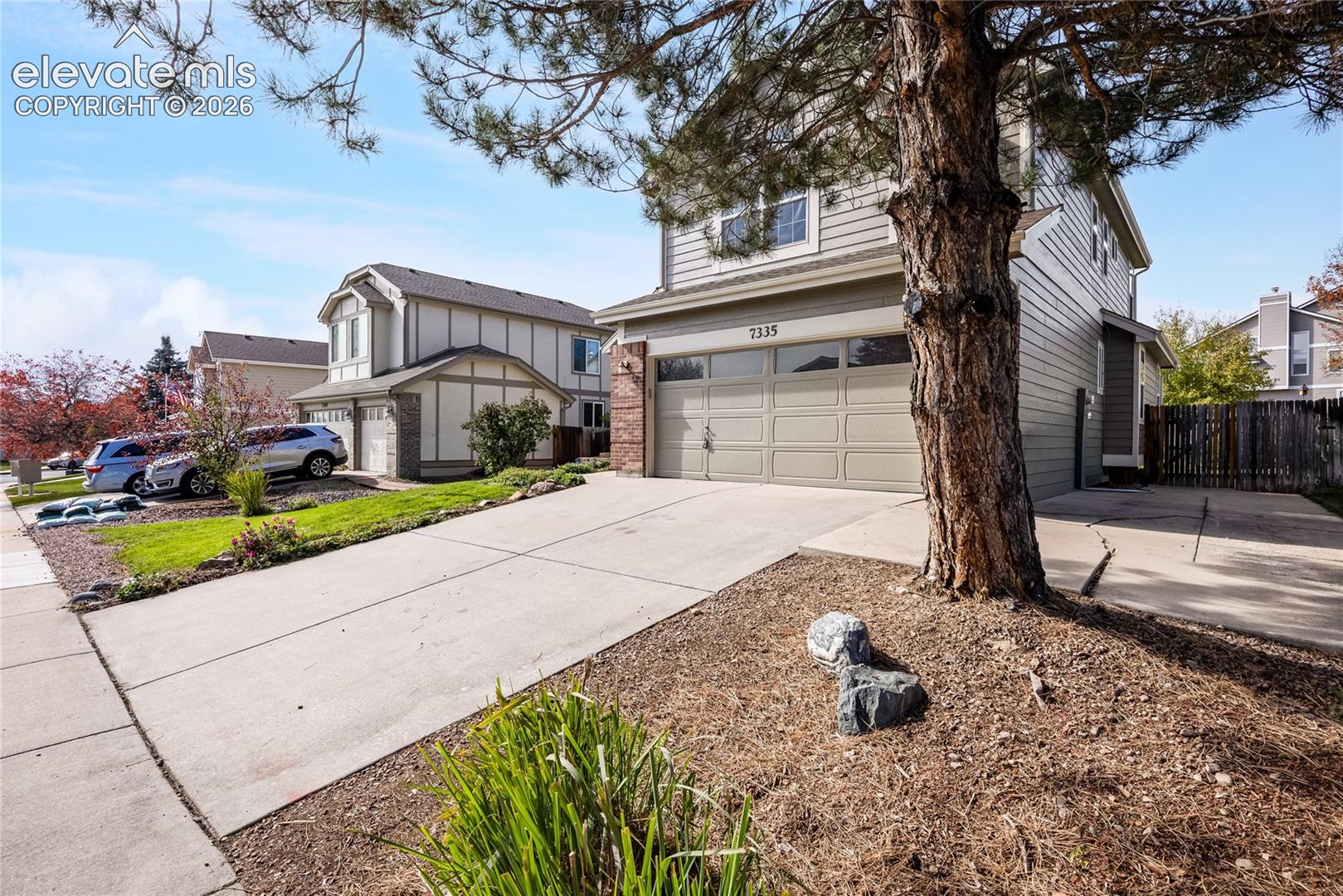 Two-story exterior featuring horizontal lap siding, attached two-car garage, concrete driveway, and brick masonry accents