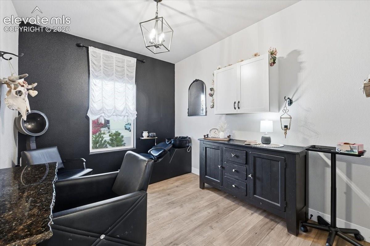 Wood-finish flooring, recessed window, dark accent wall, white upper cabinetry, and dark lower cabinetry with drawers