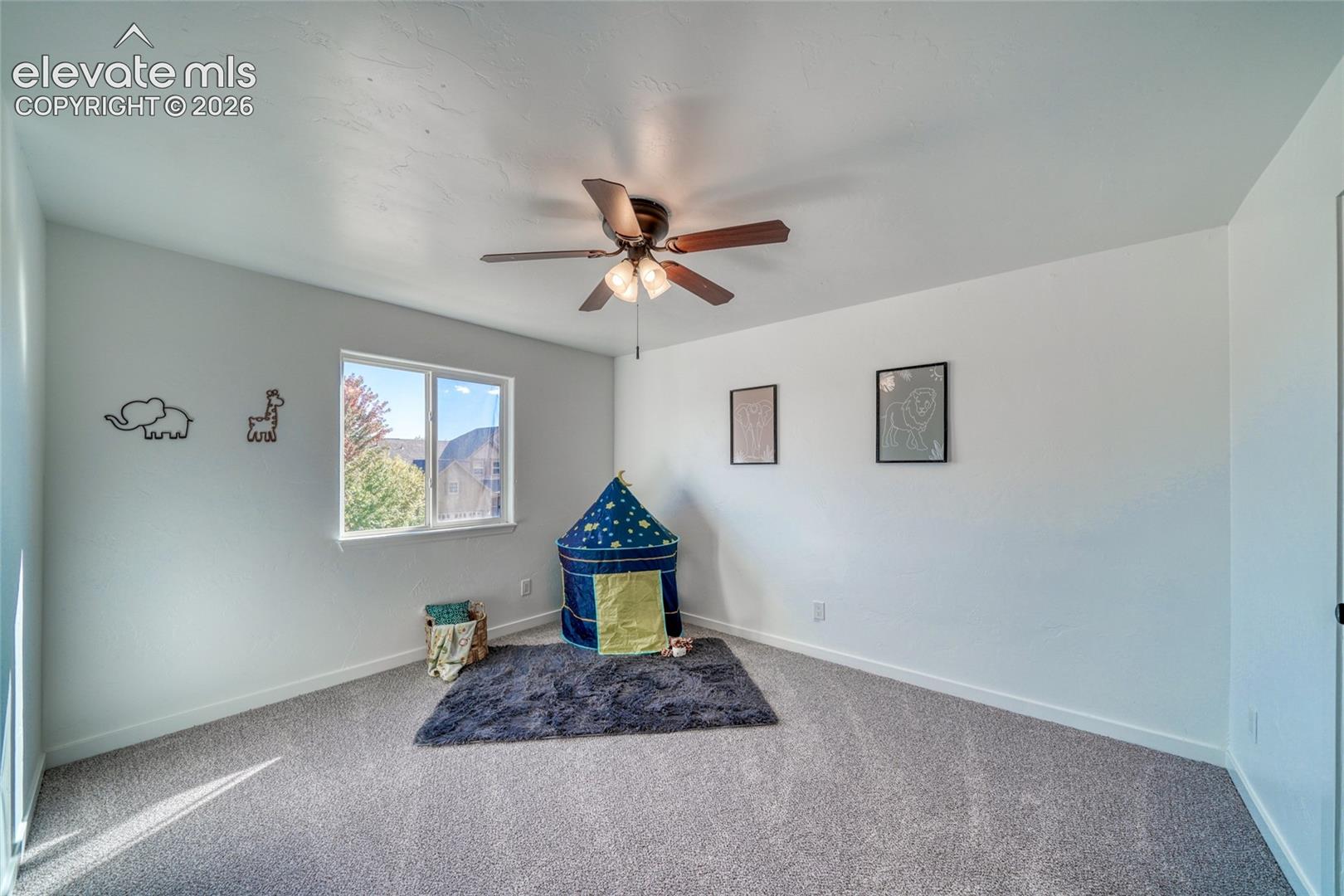Neutral wall paint, ceiling fan with integrated lighting, carpeted flooring, and a window with natural light