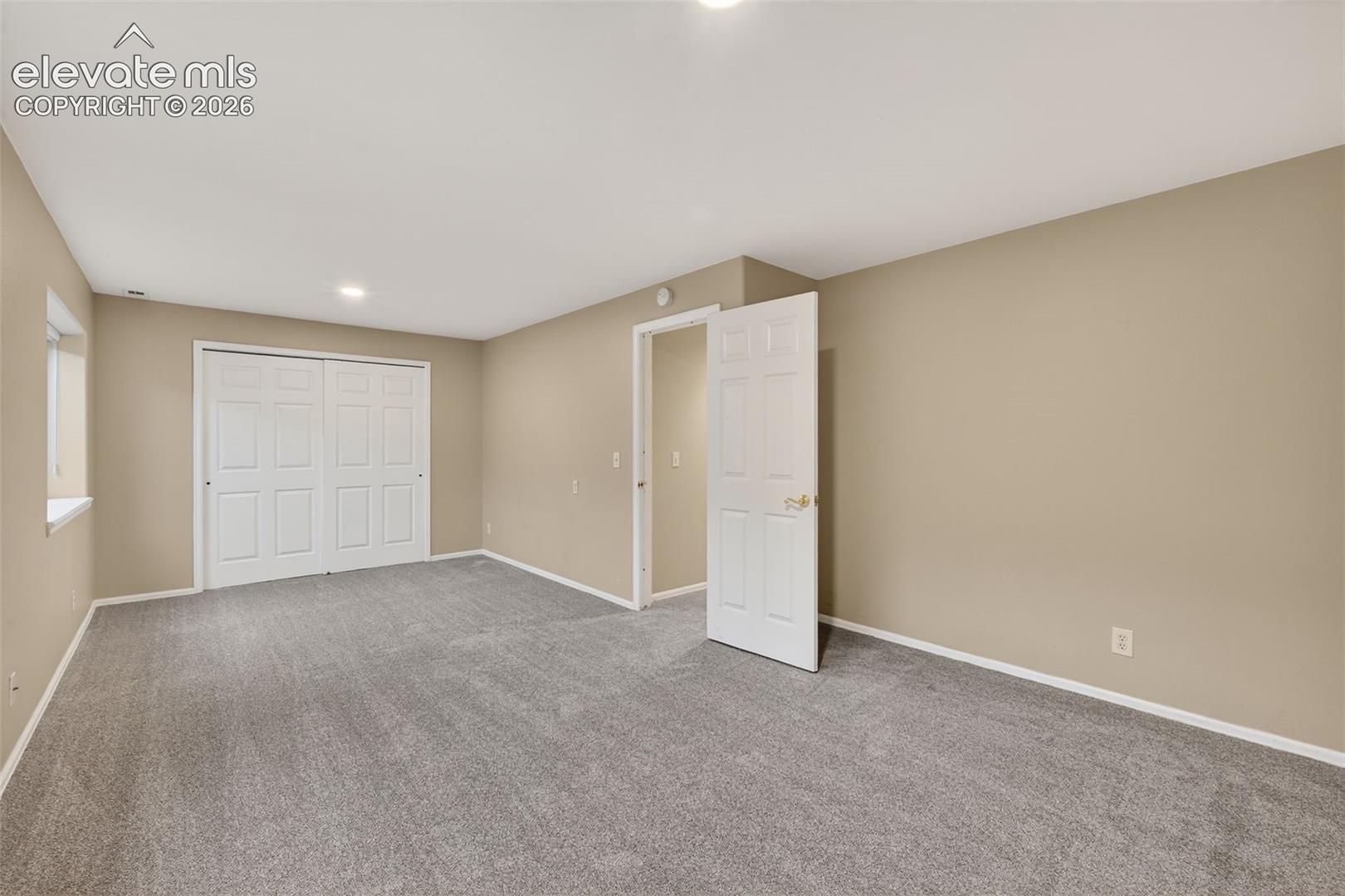 Neutral wall tones, wall-to-wall carpeting, and a double-door closet with six-panel doors