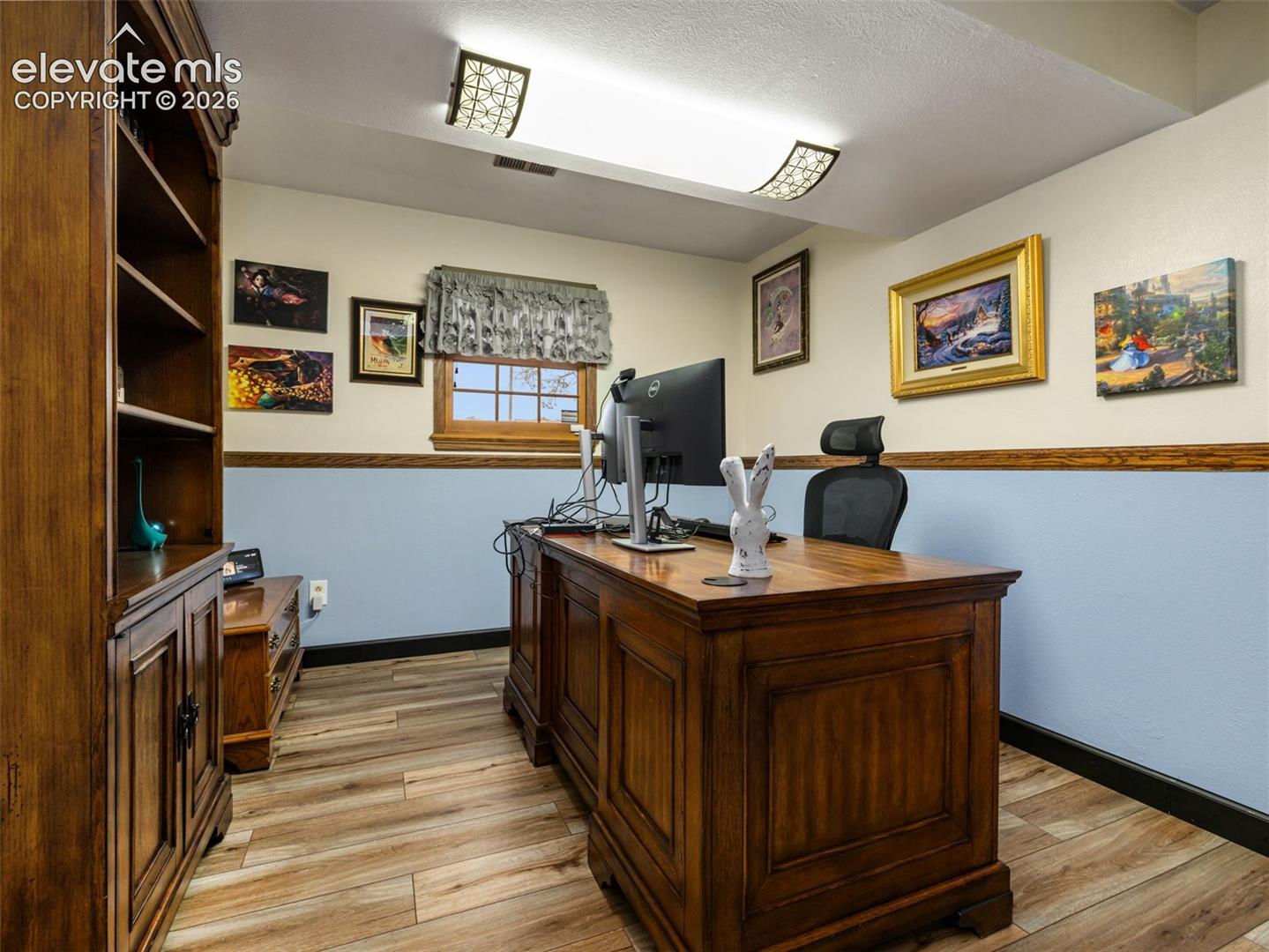 Wood-finish flooring, built-in shelving, two-tone wall treatment, and a window with wood trim