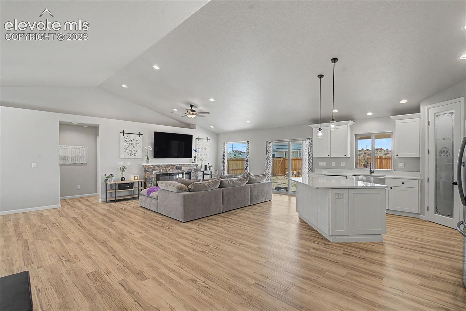 Open-concept living space featuring wood-finish flooring, a vaulted ceiling, and recessed lighting
