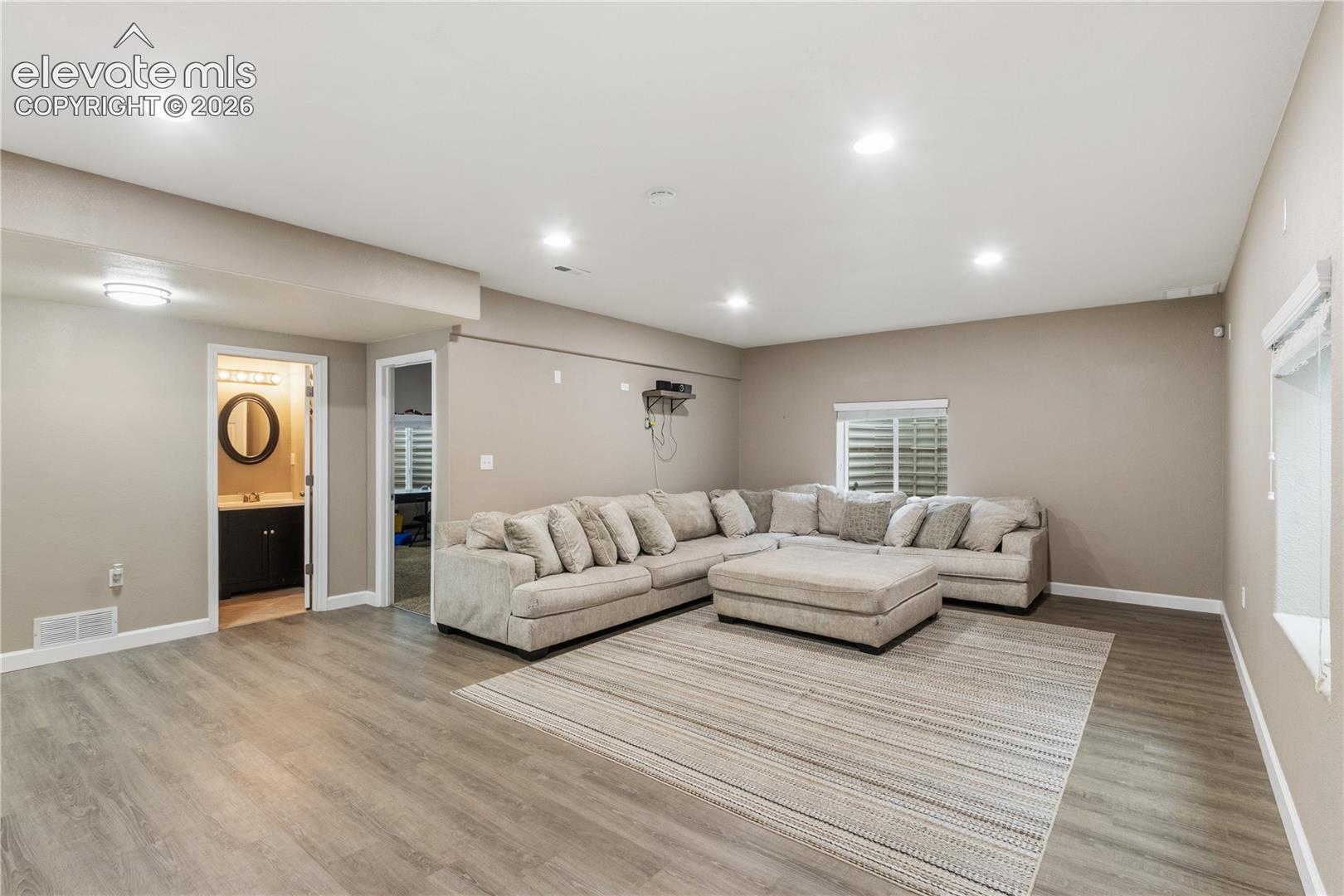 Neutral interior space featuring wood-finish flooring, recessed lighting, and a window with a window well