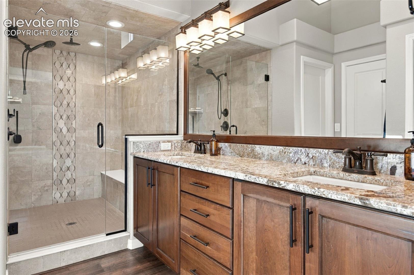 Walk-in shower with a glass enclosure, dual shower heads, and built-in bench