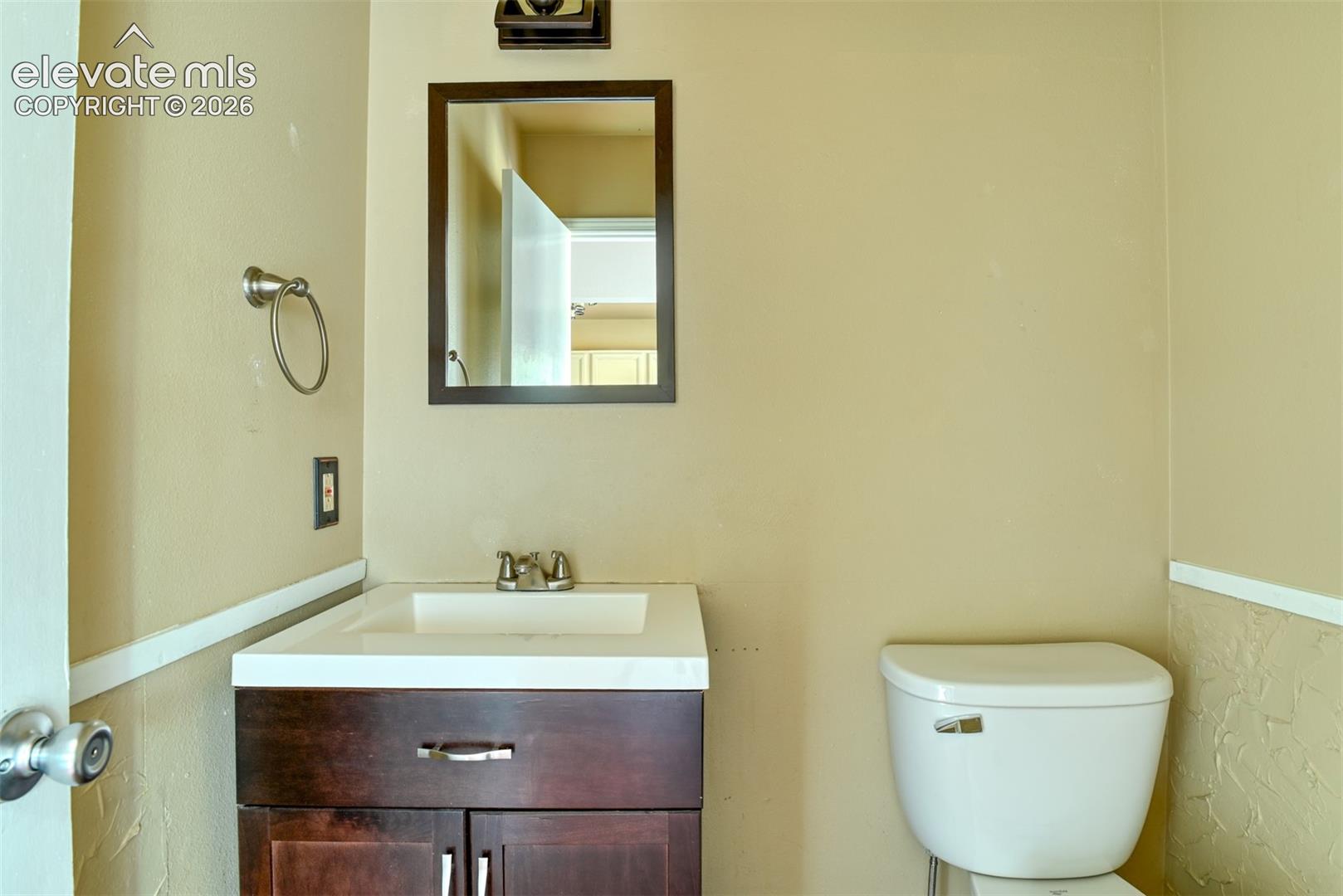 Dark wood-finish vanity with integrated sink, chrome faucet, and rectangular mirror