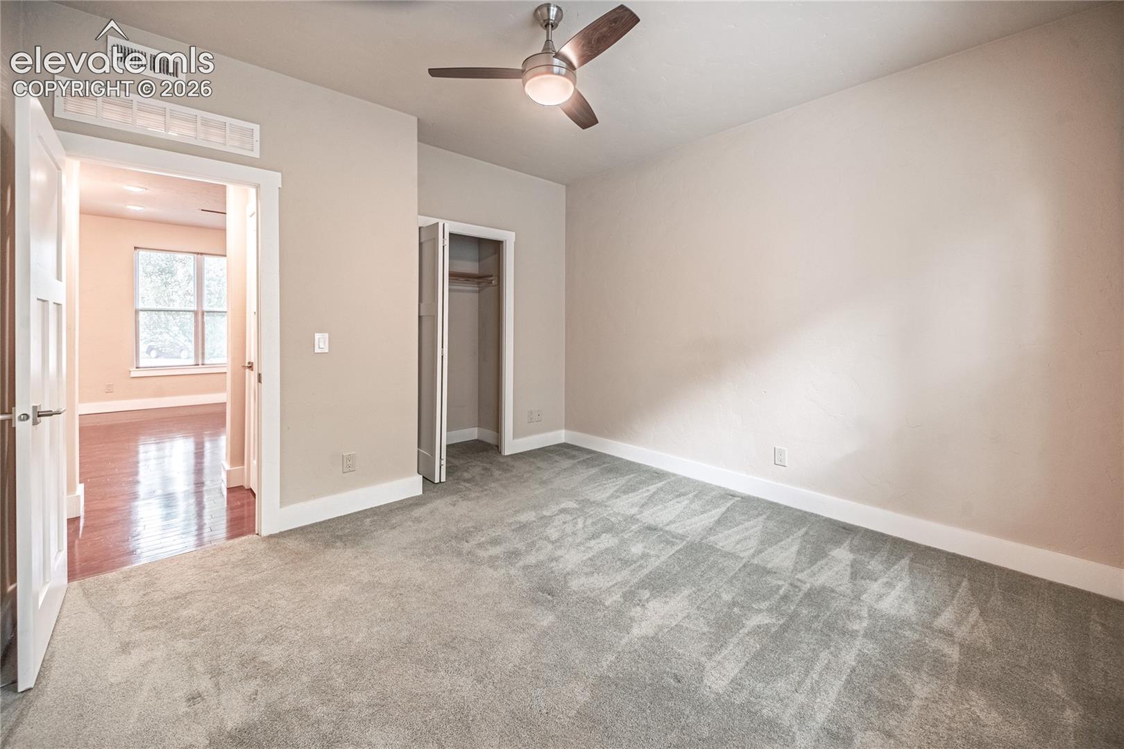 Carpeted room featuring a ceiling fan with integrated lighting, a bi-fold closet, and baseboard molding