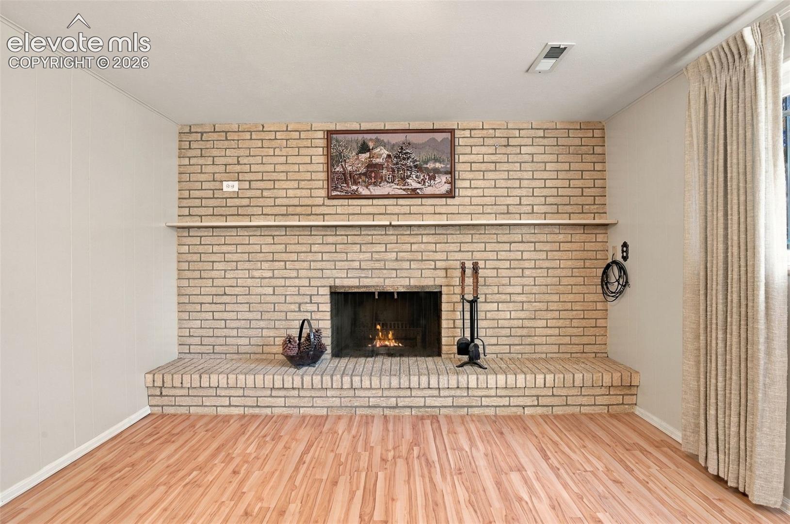 Full-height masonry fireplace with a raised brick hearth and integrated wooden mantel, complemented by wood-finish flooring