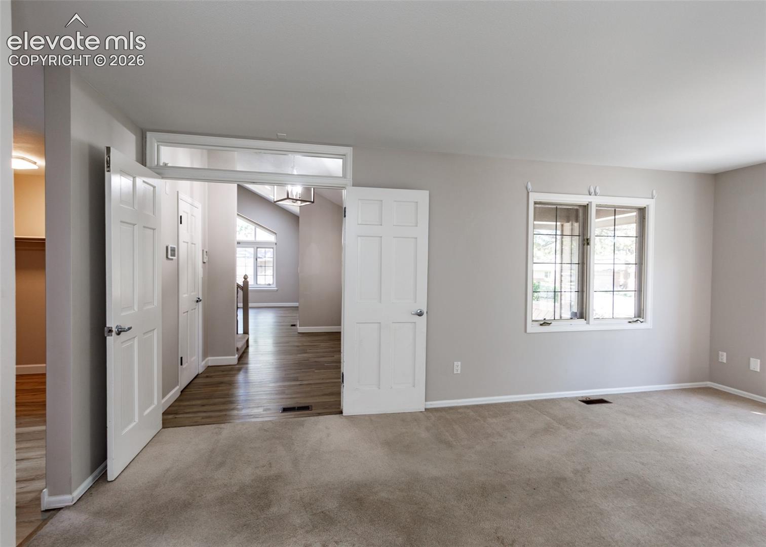 Carpeted room featuring a window with grid pattern and light gray wall paint