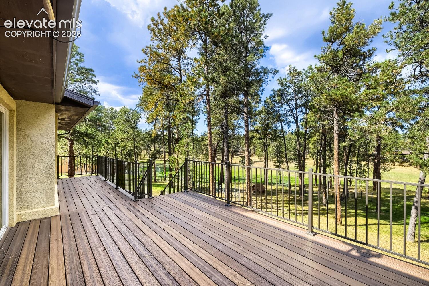 Expansive wood-finish deck with metal railings and a textured stucco exterior