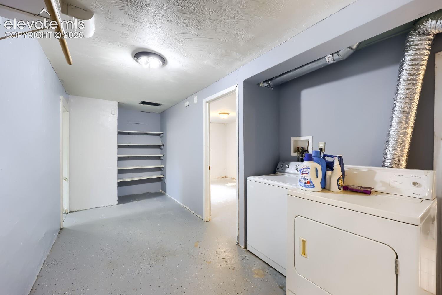 Dedicated laundry area featuring a washer and dryer, built-in shelving, and overhead lighting