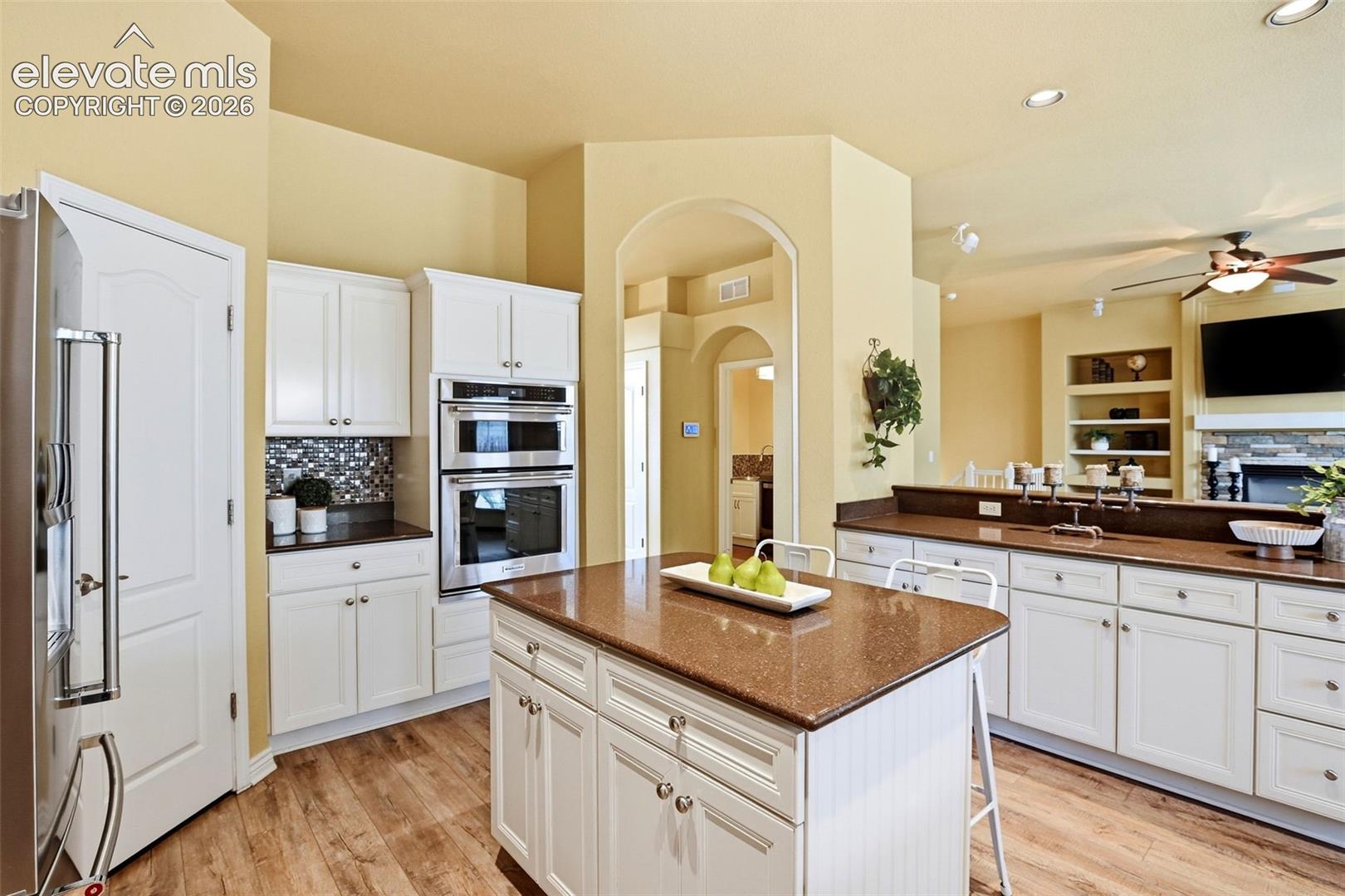 Kitchen featuring white cabinetry, built-in double ovens, a central island with countertop, and wood-finish flooring