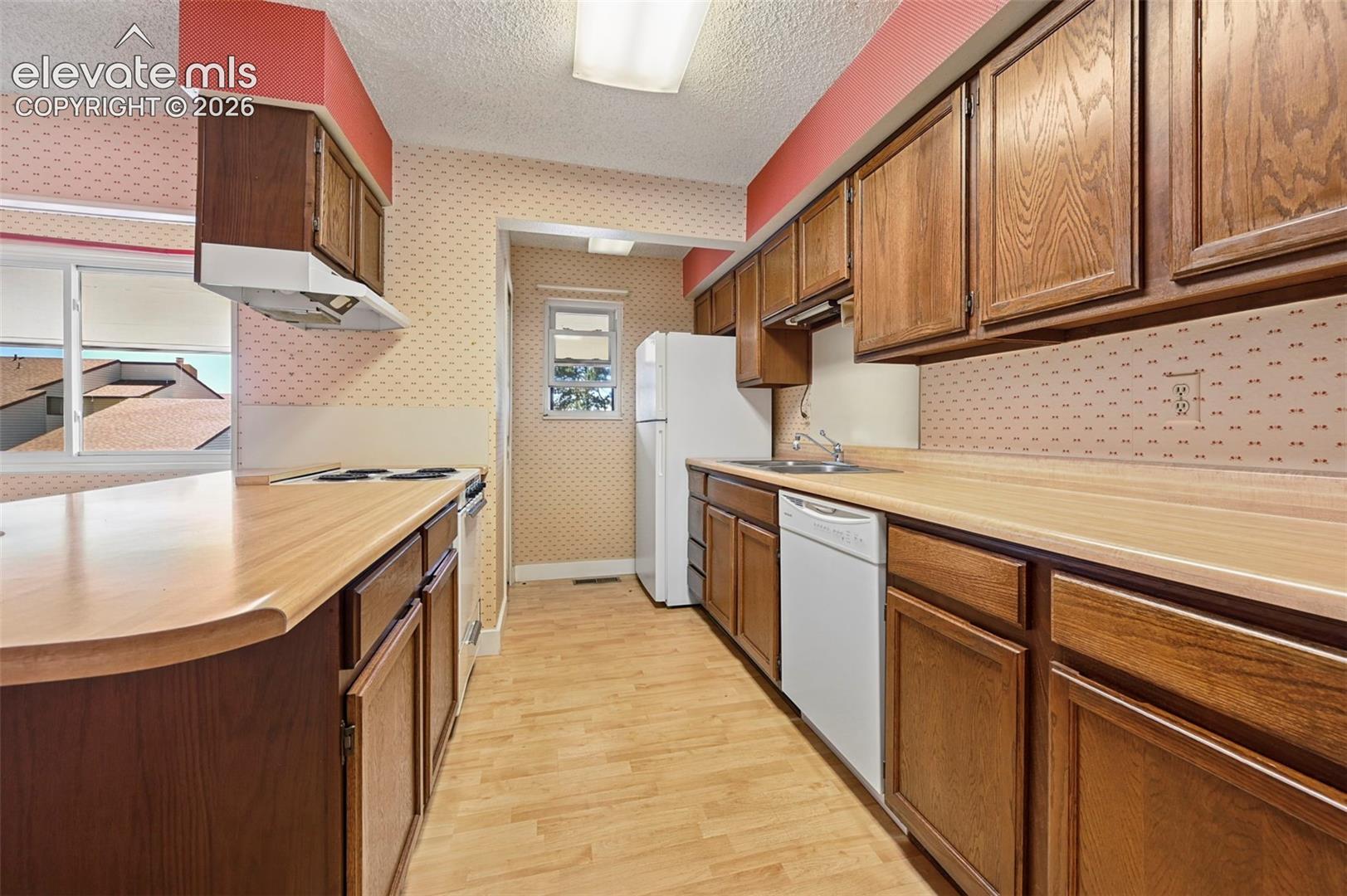 Kitchen with extensive wood-finish cabinetry, light wood-finish countertops, and light wood-finish flooring