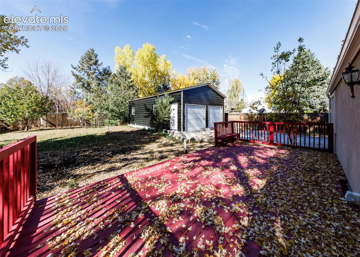 Raised outdoor deck featuring painted wood railings and a detached two-car garage with white roll-up doors
