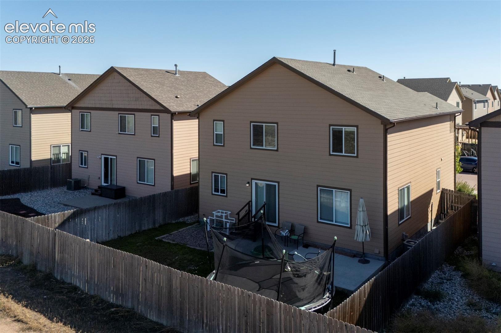 Private rear yard with a concrete patio, wood fencing, and a gravel area