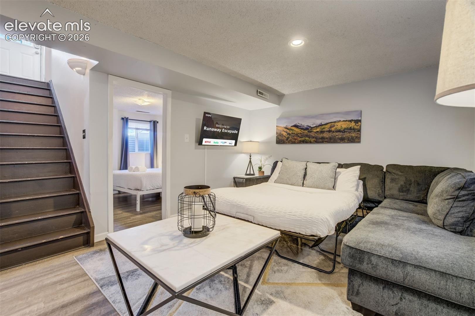 Wood-finish flooring, recessed lighting, and a wall-mounted television