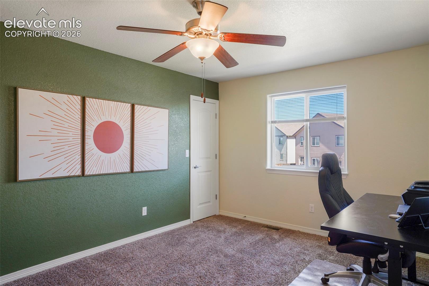 Window with blinds, ceiling fan with light fixture, textured accent wall, paneled door, and carpet flooring