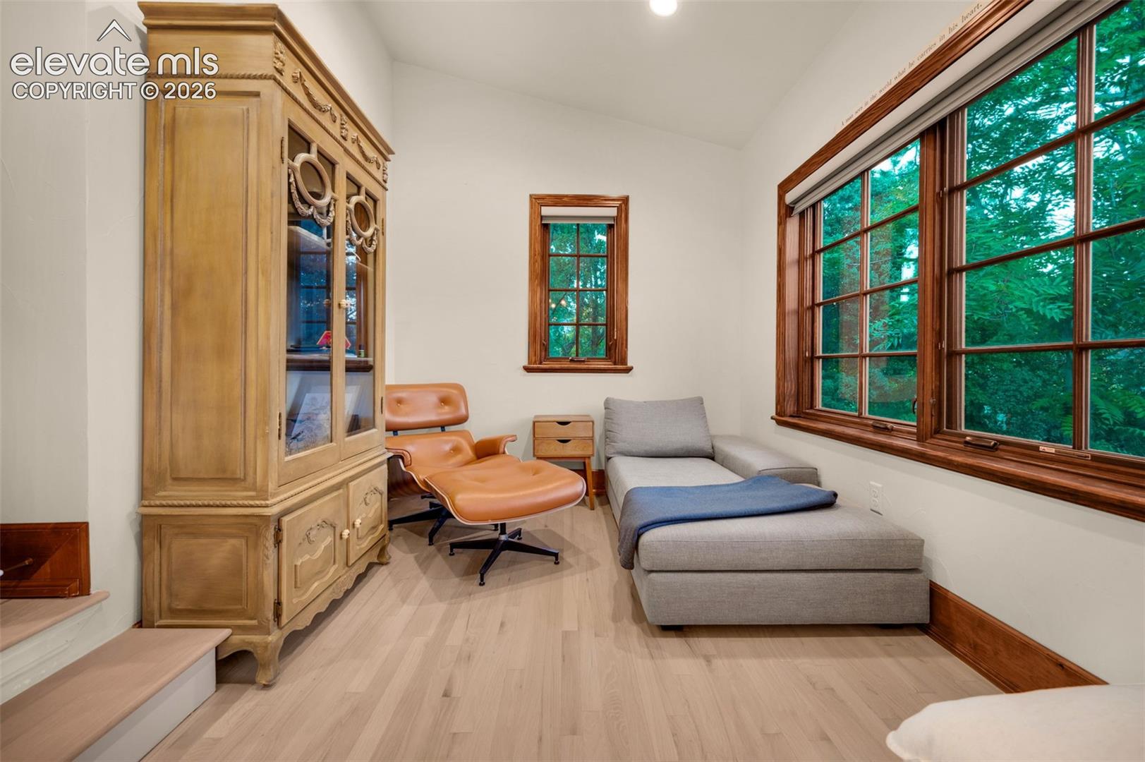 Light-toned wood-finish flooring, vaulted ceiling, and expansive windows framed by natural wood trim