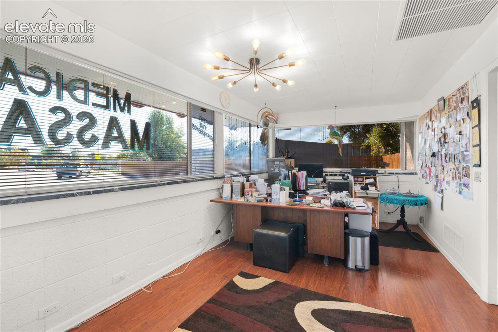 Expansive windows with stone sills, wood-finish flooring, and a multi-arm sputnik-style ceiling light fixture