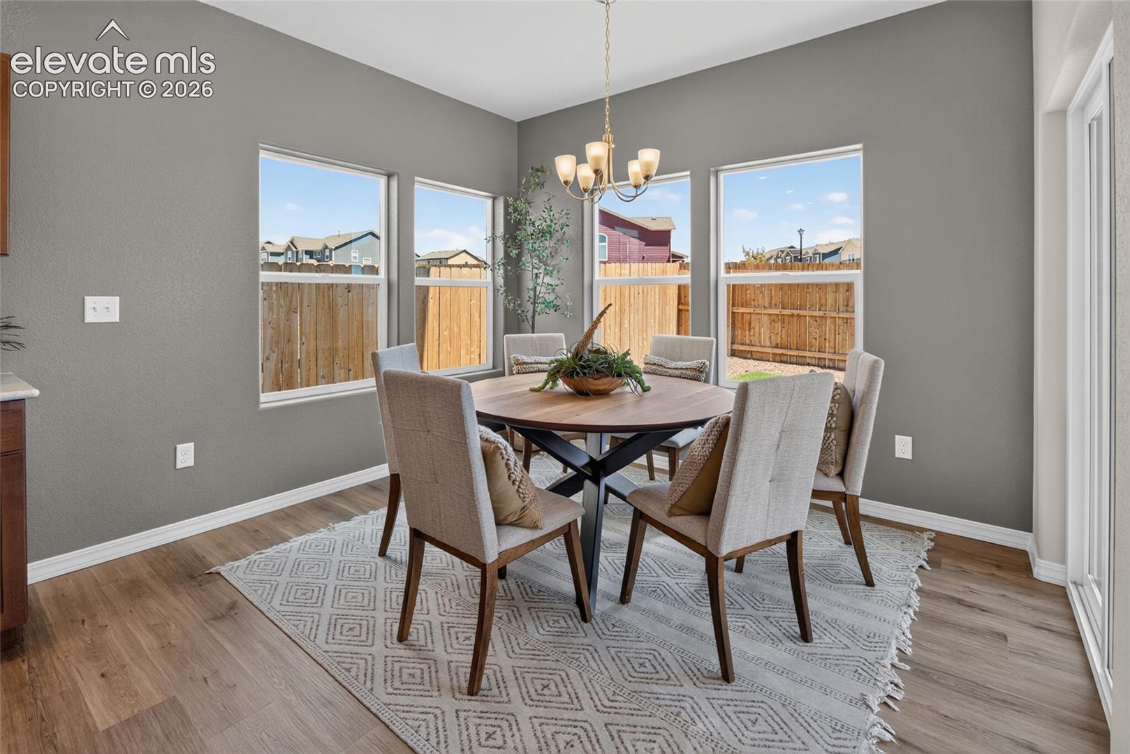 Dining space featuring wood-finish flooring, multi-pane windows, and an overhead chandelier with five frosted glass shades