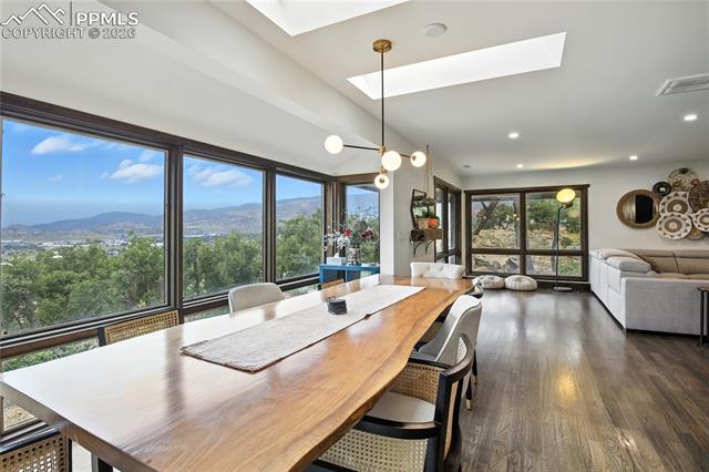 Dining area with a skylight, a mountain view, dark wood-style floors, and recessed lighting
