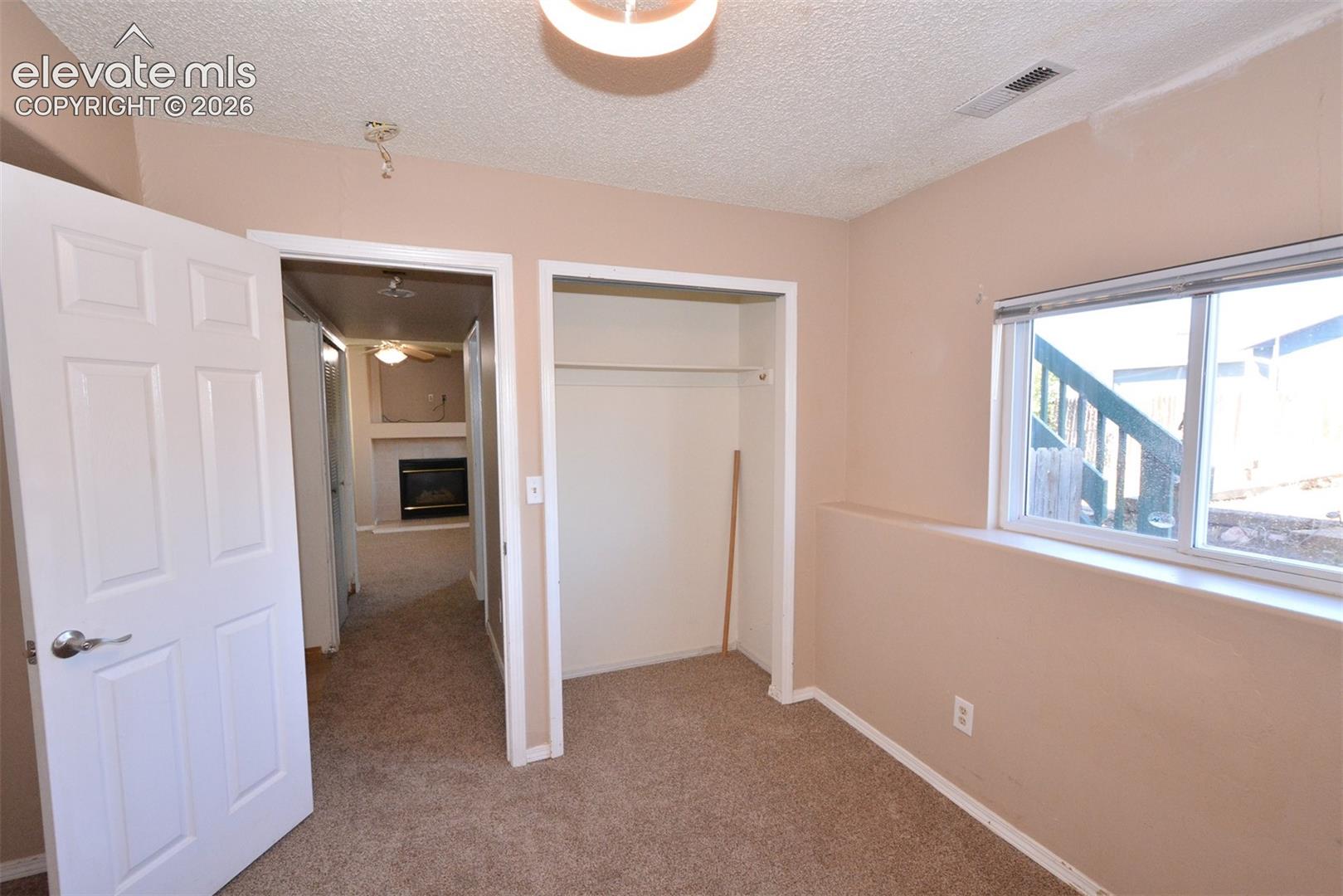Carpeted room with a window, a built-in closet, and a white six-panel door