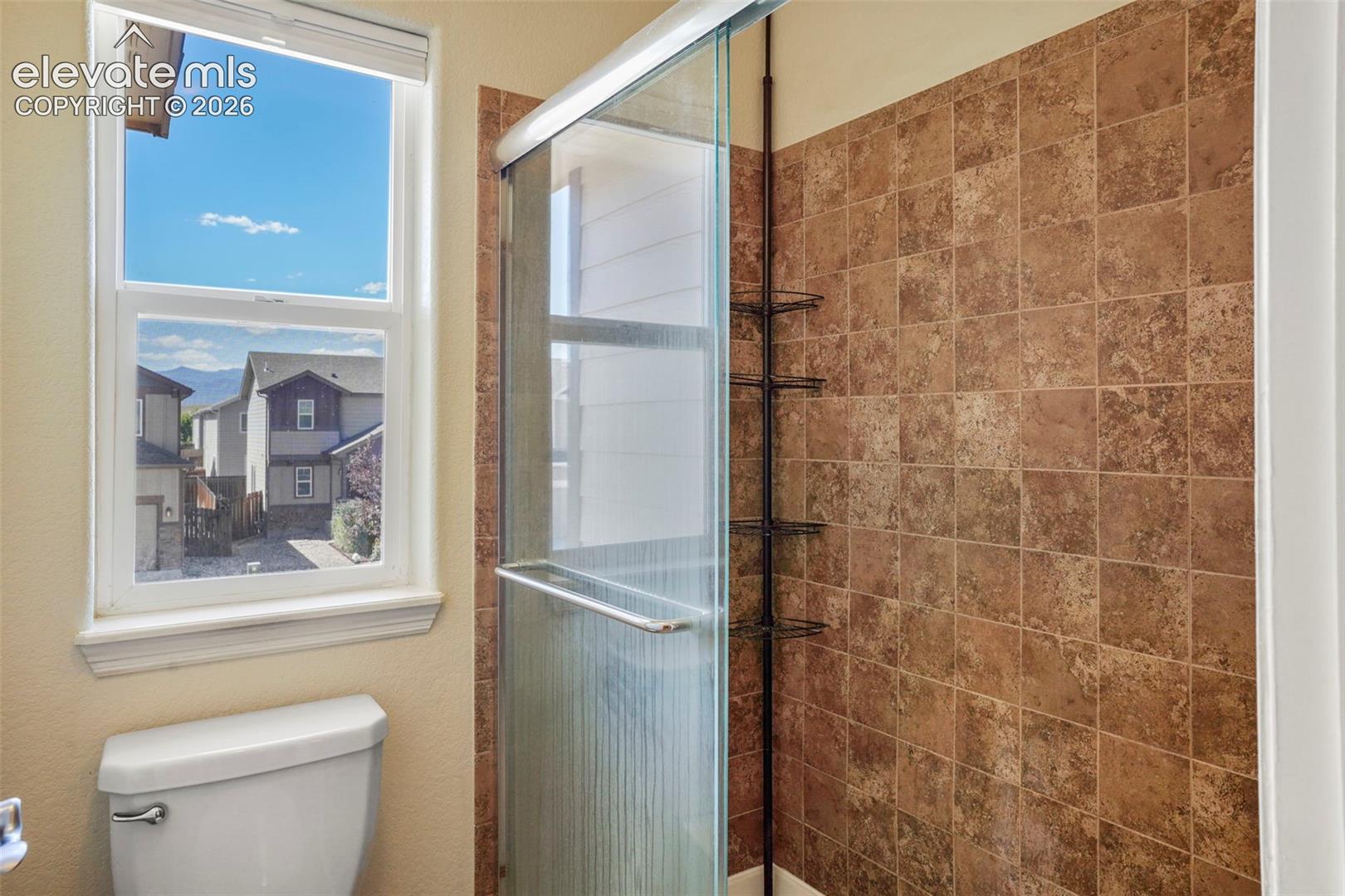 Tiled shower enclosure with a glass door, complete with an integrated shower caddy