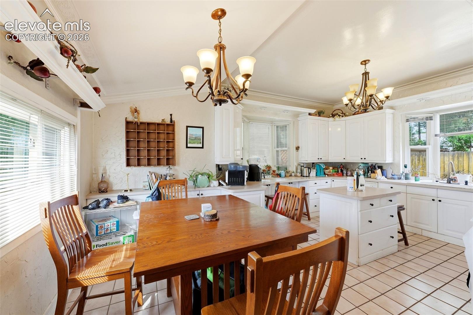 White cabinetry with dark hardware, recessed lighting, tile flooring, and a kitchen island with storage