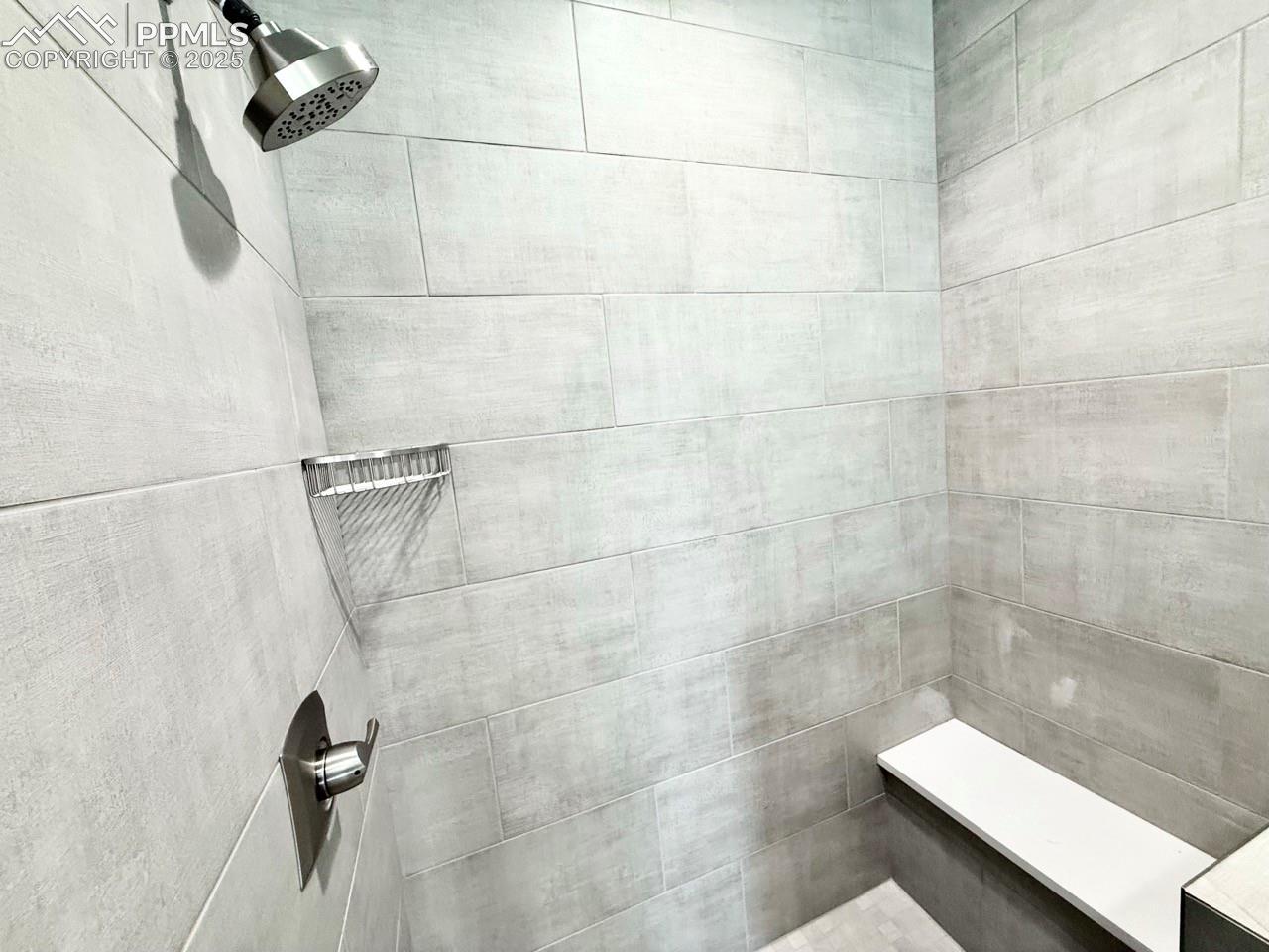 Luxurious Primary Bathroom with Quartz Countertop, Deep Soaking Tub, Tiled Shower with Bench and Glass Door, and a Heated Mirror to avoid Fogging.