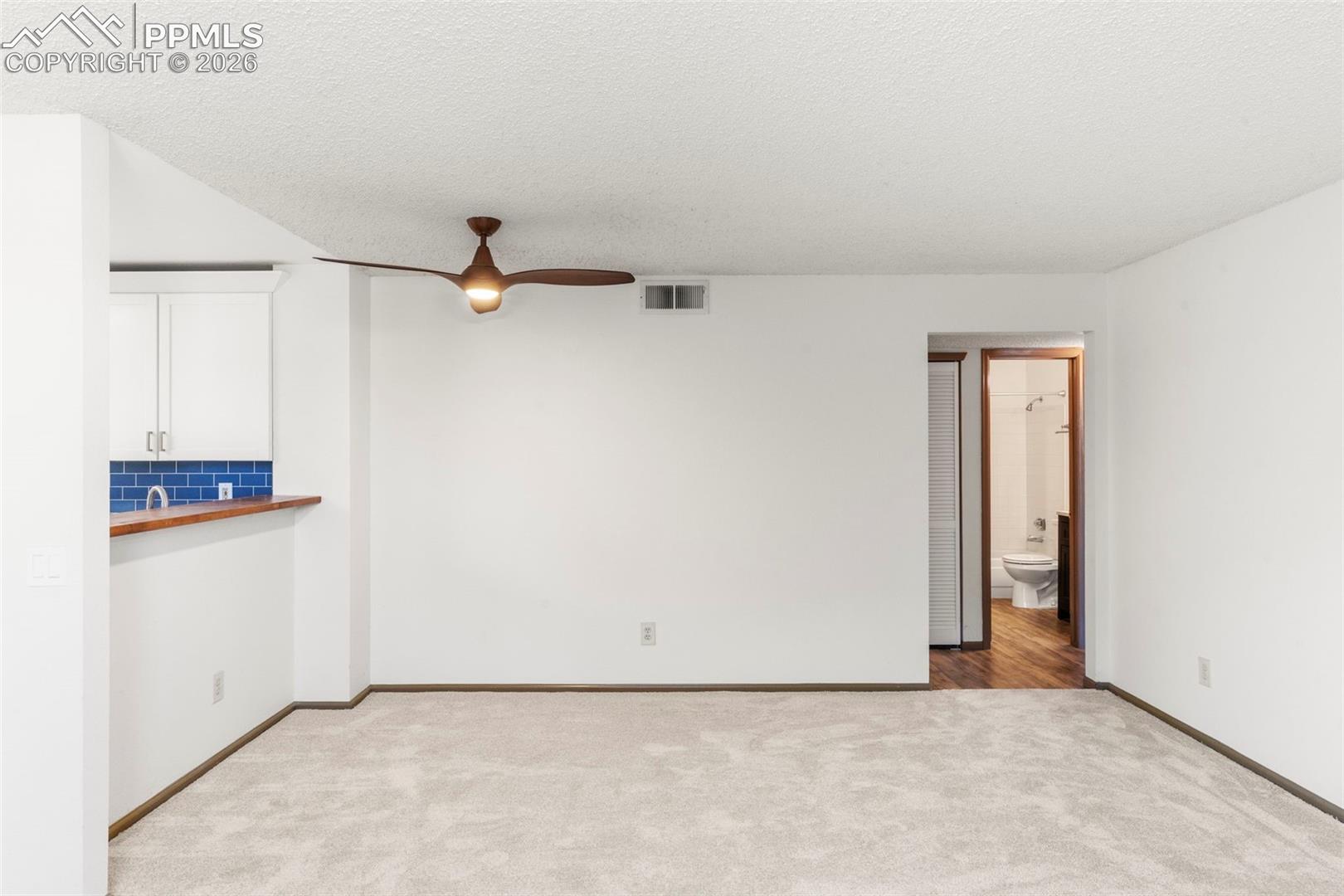 Spare room with light colored carpet, a ceiling fan, and a textured ceiling