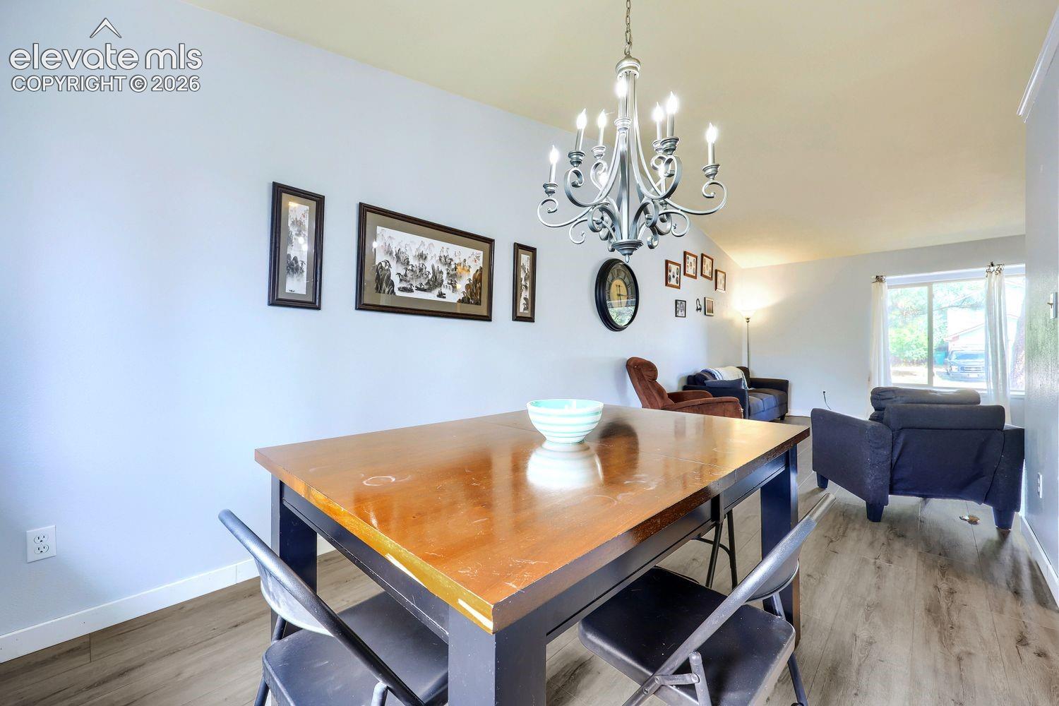 Dining area with wood-finish flooring, featuring a classic chandelier and light-toned walls