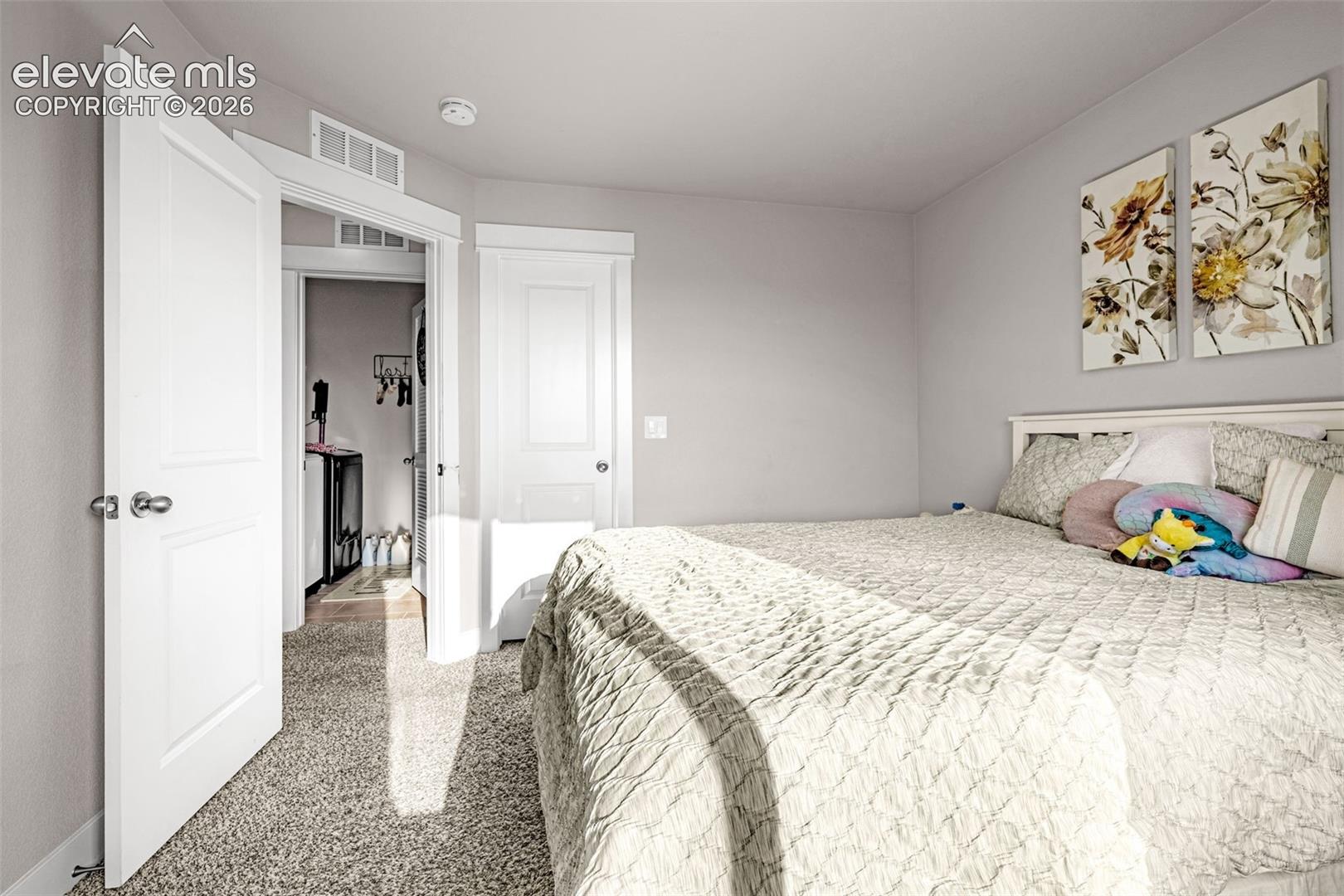 Neutral toned bedroom featuring light grey walls, white trim, and textured carpet flooring