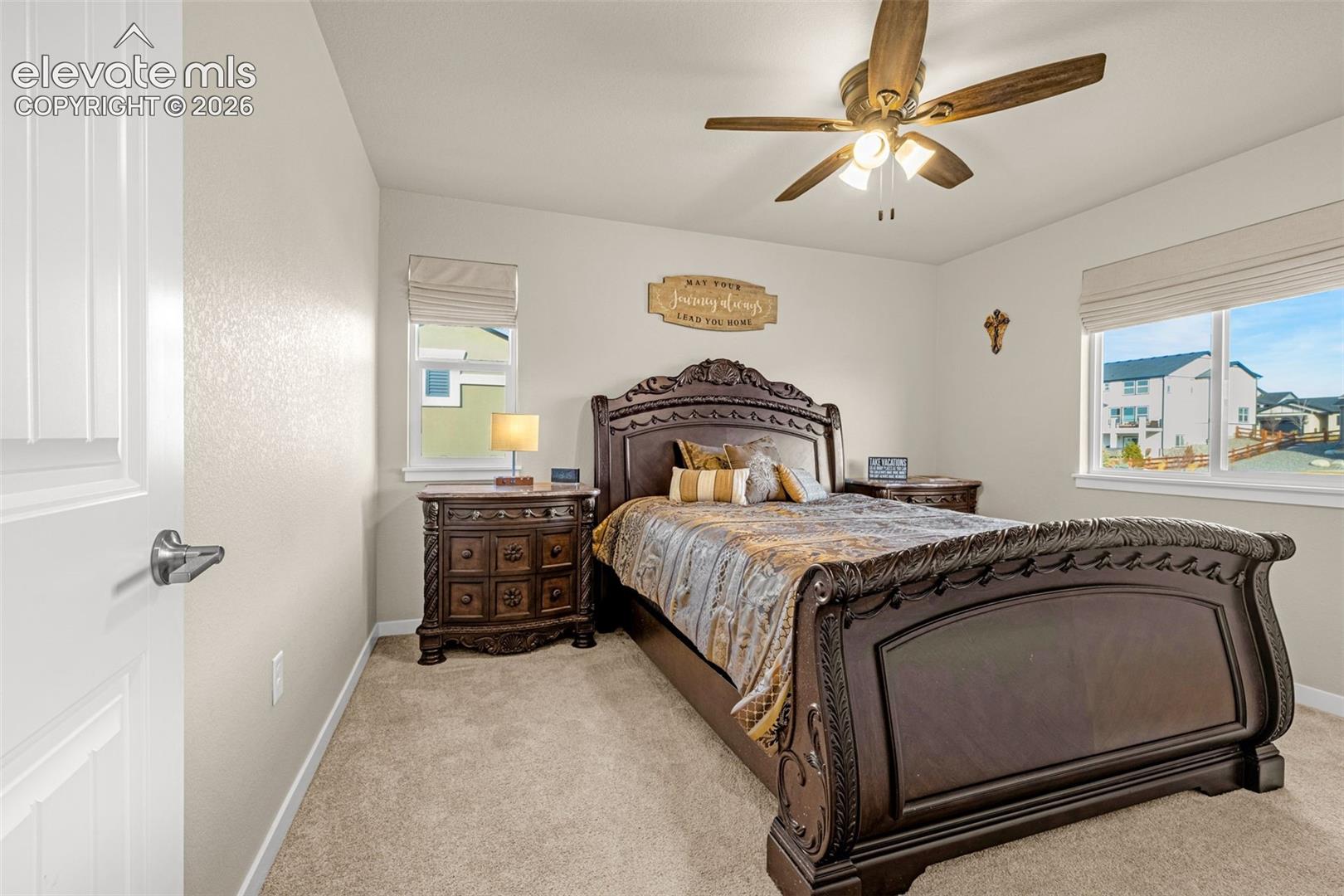 Neutral-toned interior featuring carpeting, a ceiling fan with integrated lighting, and multiple windows