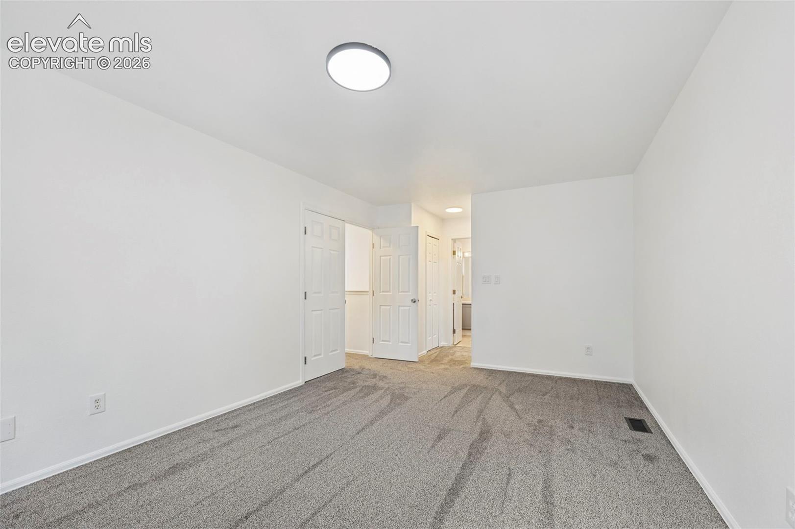 Neutral wall color with gray carpeting and a flush-mount ceiling light