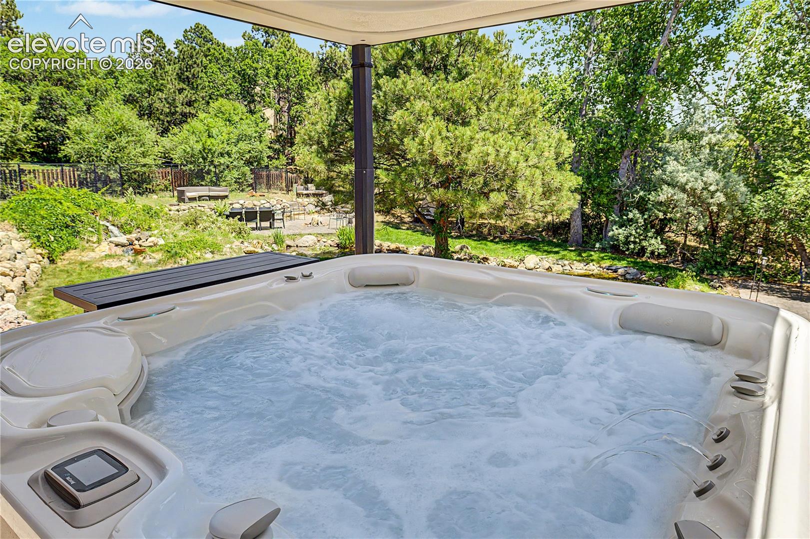 A hot tub tucked beneath its own pergola adds a resort-like feature to the outdoor living space.