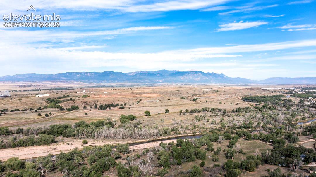 Expansive landscape with a winding river, mature tree lines, and distant mountain ranges