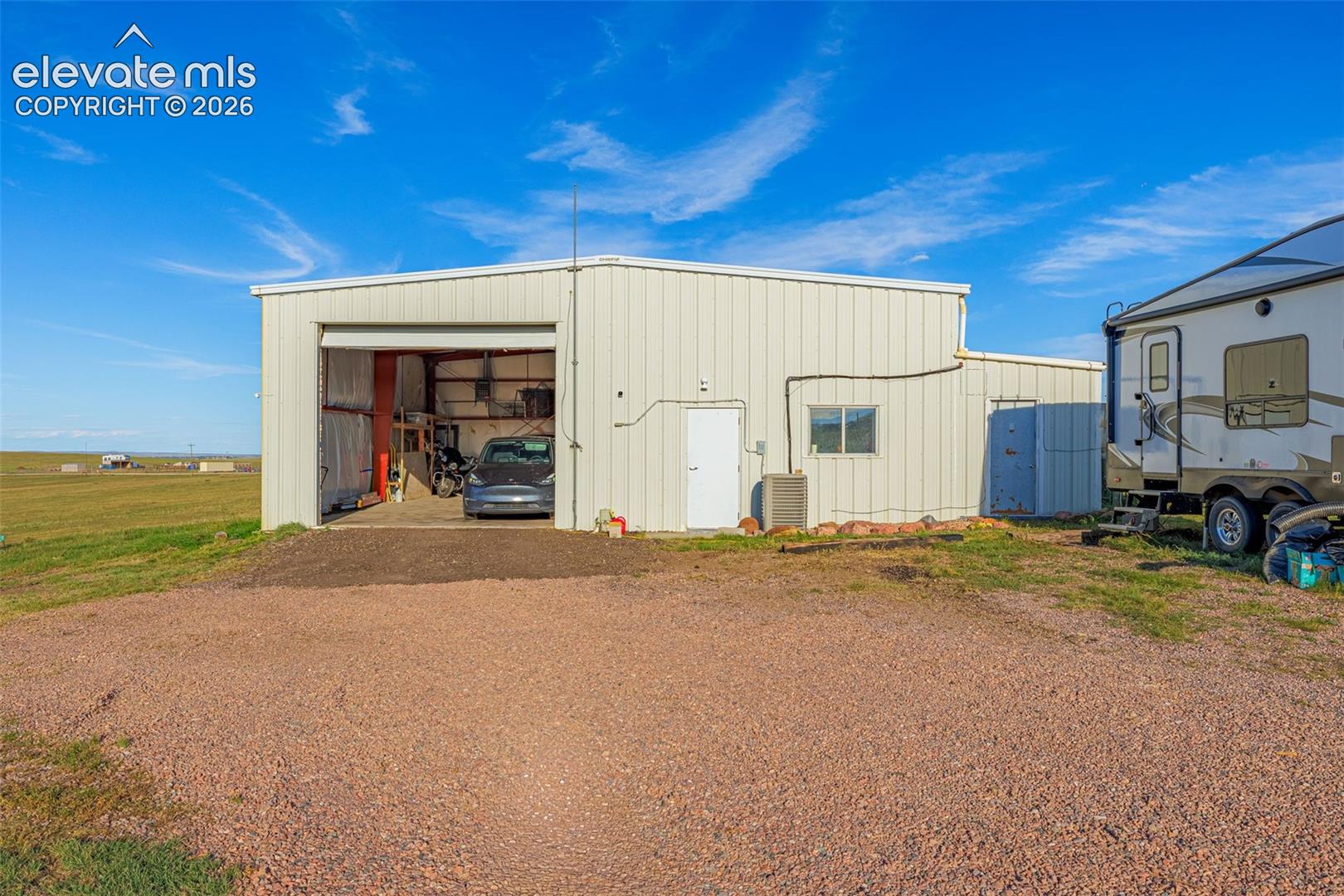 Metal-sided outbuilding featuring a roll-up garage door, single entry door, and a small window