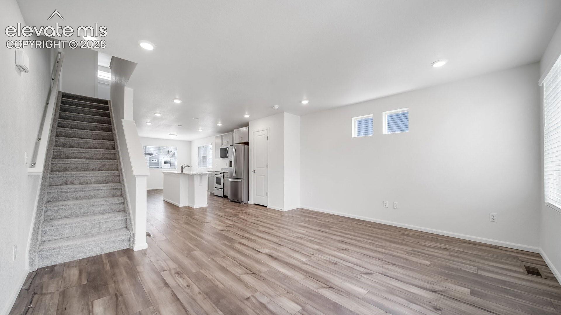 Open-concept living space with wood-finish flooring, recessed lighting, and a kitchen featuring a center island and stainless steel appliances
*photos of a model home*