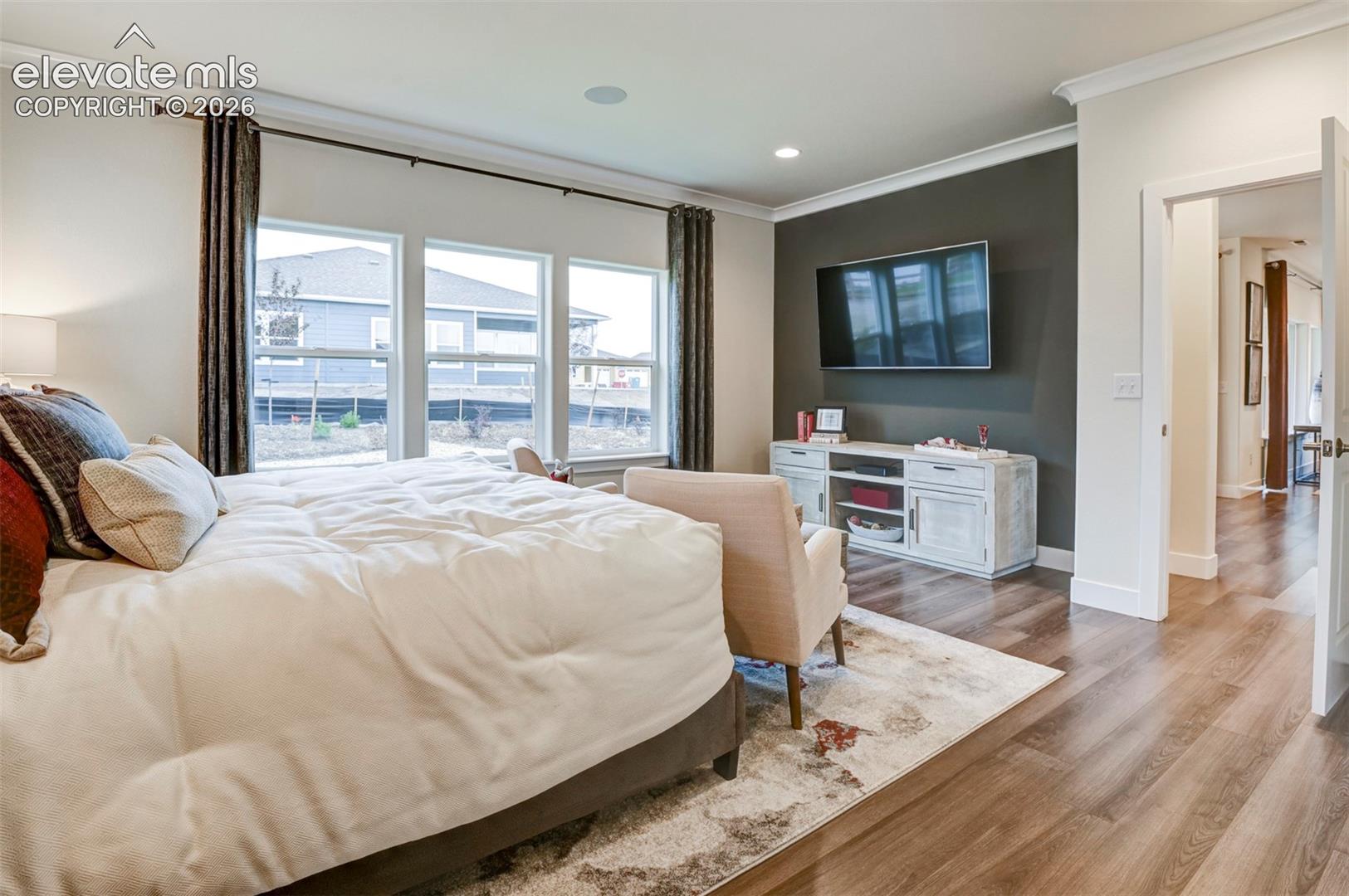 Wood-finish flooring throughout, ceiling crown molding, recessed lighting, and a multi-panel window unit