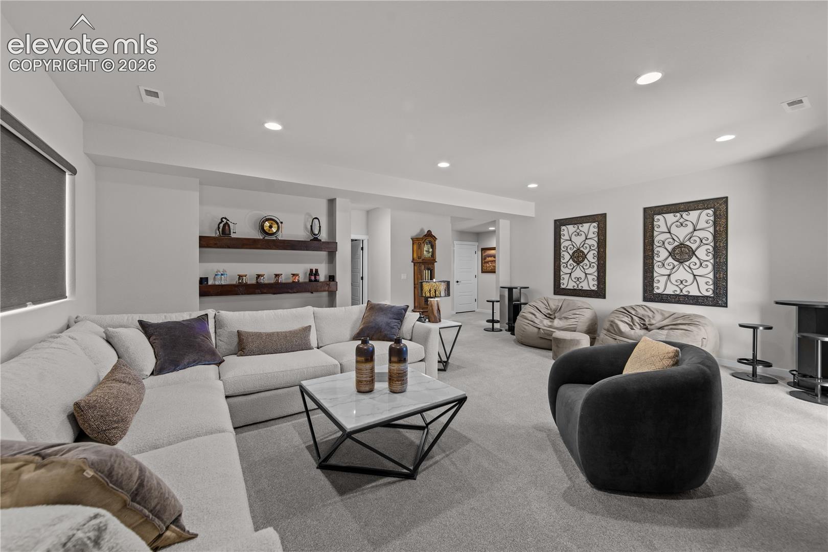 Spacious room featuring recessed lighting, neutral carpeting, and built-in wood shelving